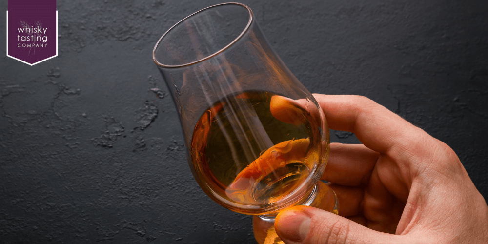 man about to taste whisky from tulip-shaped glass